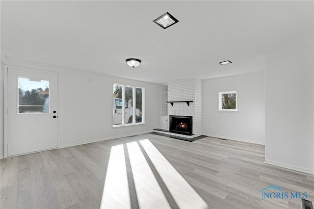 unfurnished living room with a fireplace, light wood-style floors, and baseboards