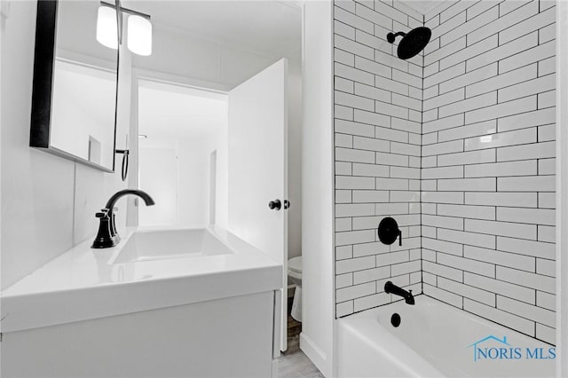 full bath featuring bathtub / shower combination, wood finished floors, toilet, and vanity