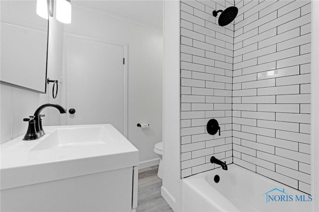 bathroom featuring wood finished floors,  shower combination, ornamental molding, a sink, and toilet