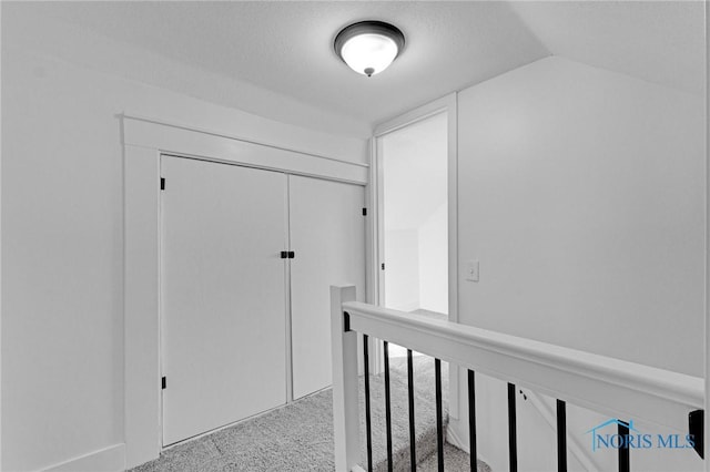 hallway featuring lofted ceiling and carpet