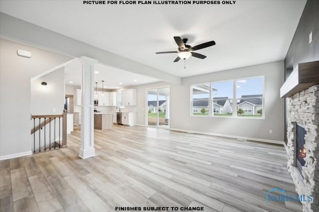 unfurnished living room featuring a stone fireplace, light wood-style flooring, baseboards, and ceiling fan