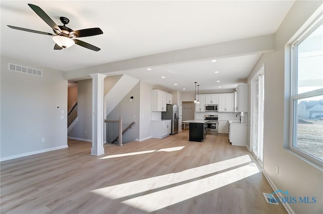 kitchen featuring light wood-type flooring, visible vents, open floor plan, stainless steel appliances, and light countertops
