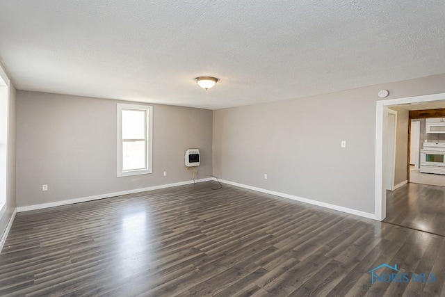 unfurnished living room featuring heating unit, dark wood-type flooring, baseboards, and a textured ceiling