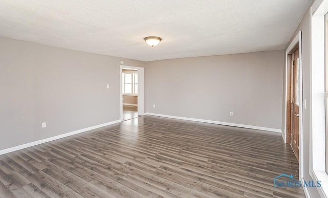 spare room with baseboards, wood finished floors, and a textured ceiling