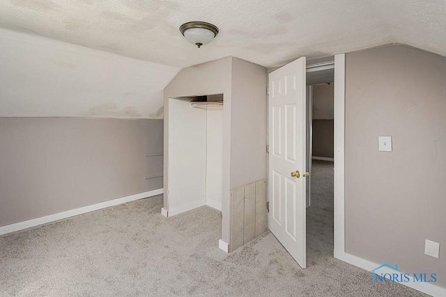 bonus room with baseboards, vaulted ceiling, carpet, and a textured ceiling