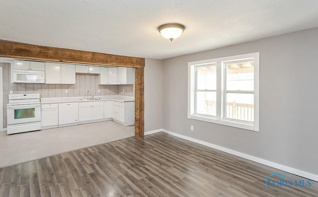 kitchen featuring a sink, white cabinetry, wood finished floors, white appliances, and decorative backsplash