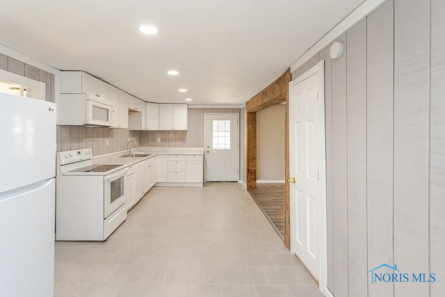 kitchen featuring decorative backsplash, light countertops, white appliances, white cabinetry, and a sink