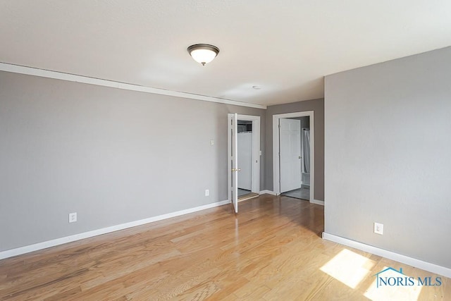 empty room with baseboards and light wood-type flooring