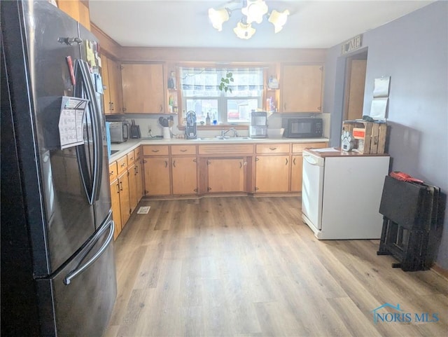 kitchen with freestanding refrigerator, an inviting chandelier, black microwave, light wood finished floors, and light countertops