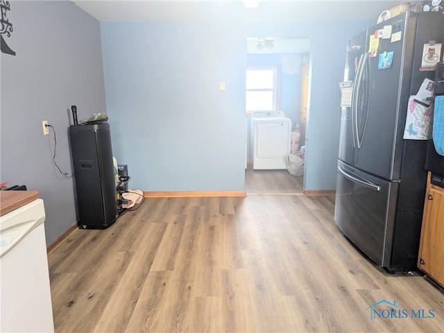 kitchen featuring washing machine and clothes dryer, light wood-style flooring, freestanding refrigerator, and baseboards