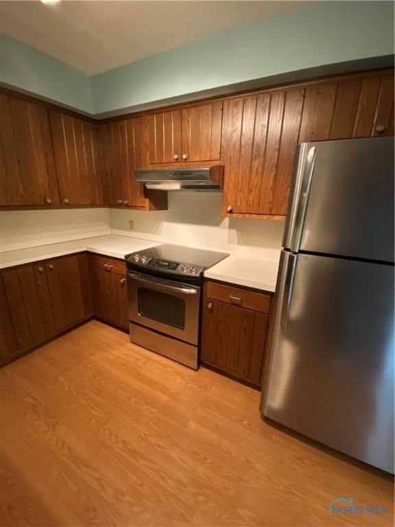 kitchen with light countertops, light wood-style floors, stainless steel appliances, and under cabinet range hood