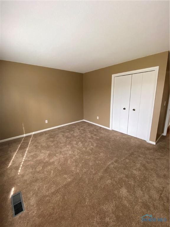 unfurnished bedroom with baseboards, visible vents, a closet, and carpet
