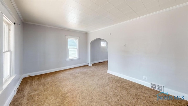 carpeted spare room with arched walkways, visible vents, crown molding, and baseboards