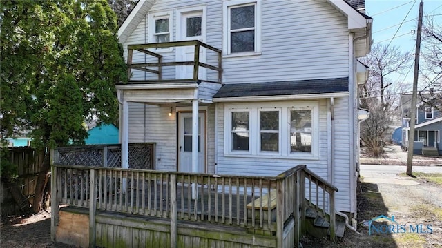 rear view of house with a shingled roof, fence, and a deck