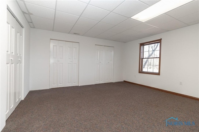 2121 County Road 4 Unit 1, Swanton, OH 43558 - unfurnished bedroom featuring baseboards, a paneled ceiling, dark colored carpet, and multiple closets
