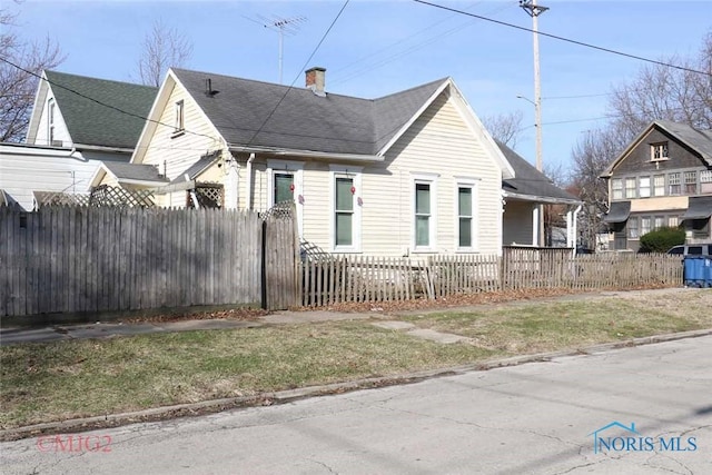 1142 Page St, Toledo, OH 43608 - view of side of property with a chimney, a fenced front yard, and roof with shingles
