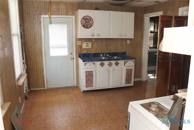 1142 Page St, Toledo, OH 43608 - kitchen featuring wooden walls, a sink, white cabinetry, dark countertops, and baseboards