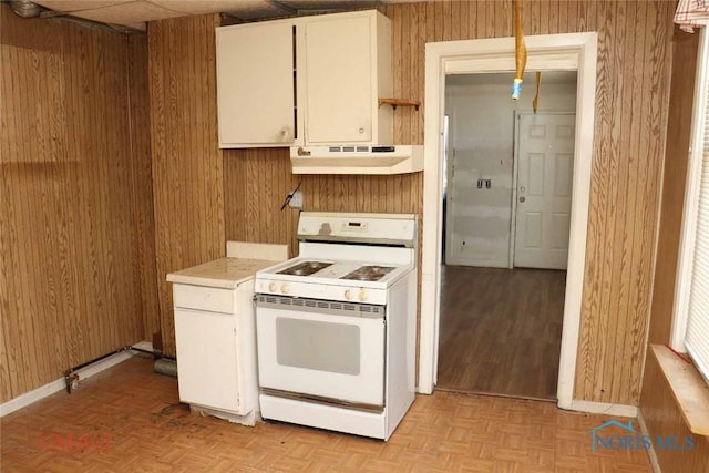 1142 Page St, Toledo, OH 43608 - kitchen featuring white stove, under cabinet range hood, wood walls, light countertops, and white cabinetry