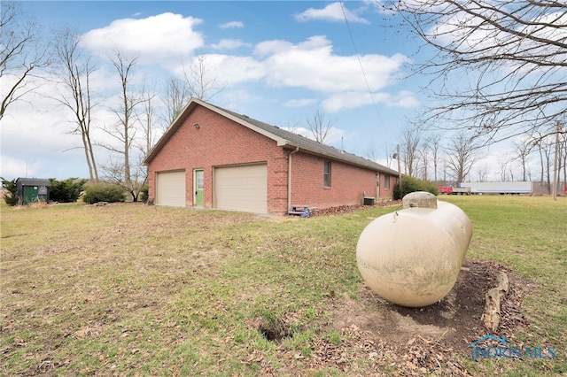 view of side of property featuring a garage, brick siding, and a yard