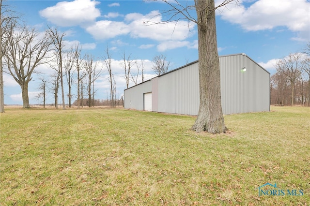 view of yard featuring an outdoor structure, a detached garage, and a pole building