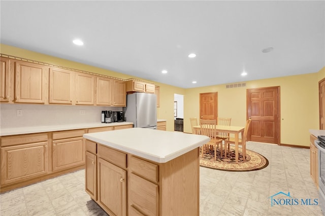 kitchen featuring light countertops, recessed lighting, freestanding refrigerator, and light brown cabinetry