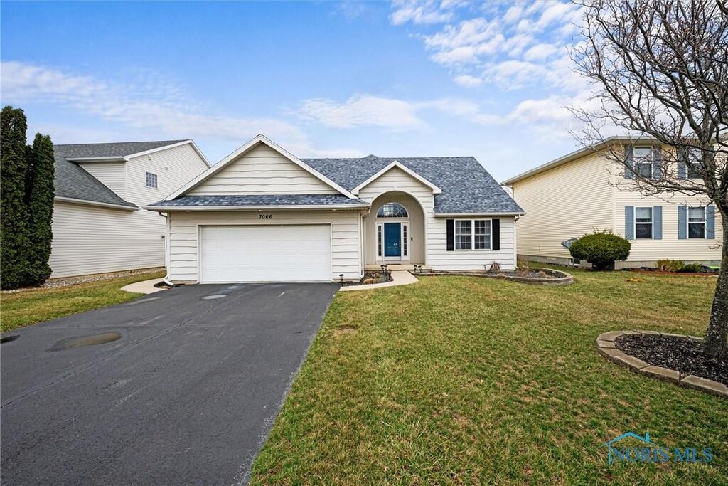 view of front facade with an attached garage, driveway, a front lawn, and roof with shingles