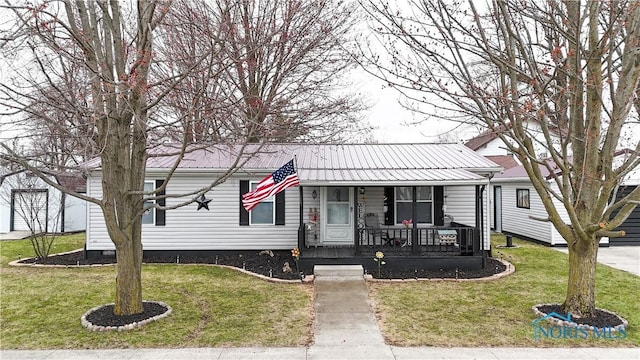 view of front facade featuring metal roof, covered porch, and a front yard