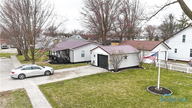exterior space featuring fence, a yard, an outdoor structure, a detached garage, and metal roof