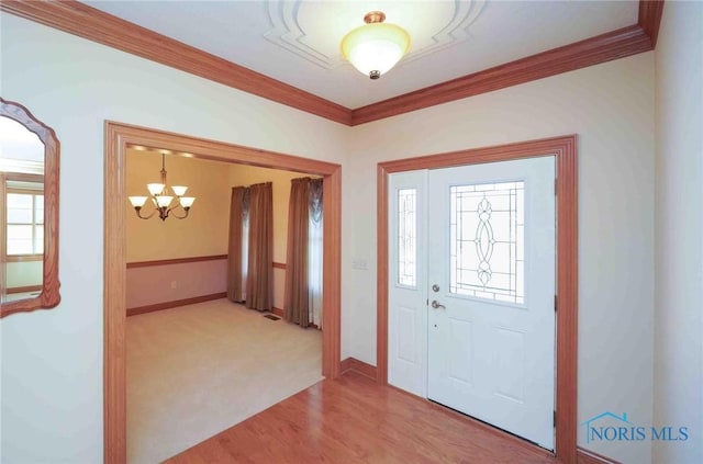 entrance foyer with baseboards, ornamental molding, an inviting chandelier, and light wood-type flooring