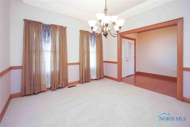 spare room with ornamental molding, carpet, baseboards, visible vents, and a notable chandelier