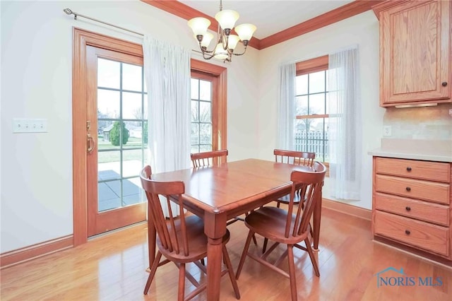 dining room with baseboards, an inviting chandelier, crown molding, and light wood finished floors