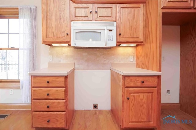 kitchen with light countertops, white microwave, and a wealth of natural light