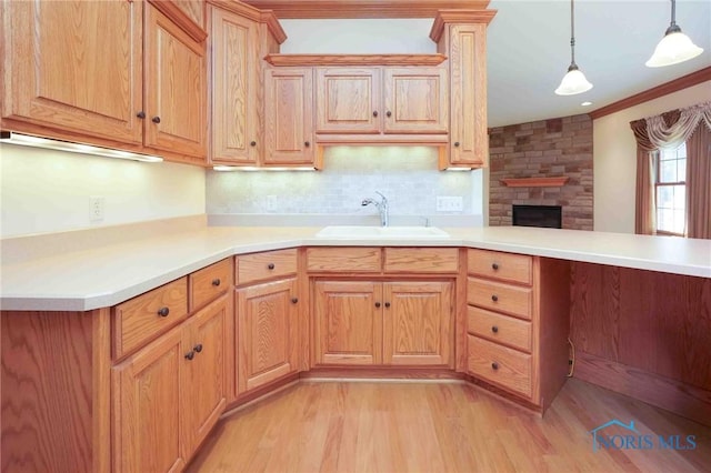 kitchen with light countertops, light wood-style flooring, a sink, and pendant lighting