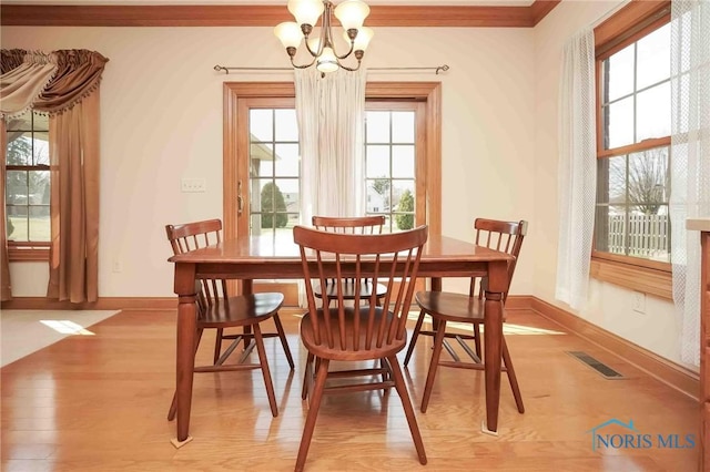 dining room with visible vents, crown molding, baseboards, light wood-type flooring, and an inviting chandelier