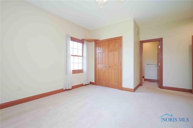 unfurnished bedroom with carpet flooring, baseboards, a closet, and visible vents
