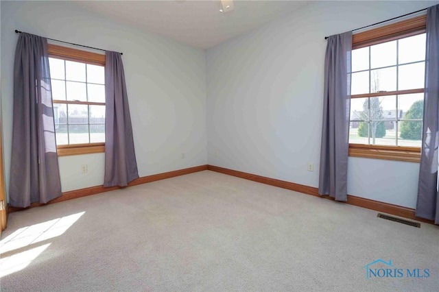 spare room with baseboards, visible vents, and carpet floors