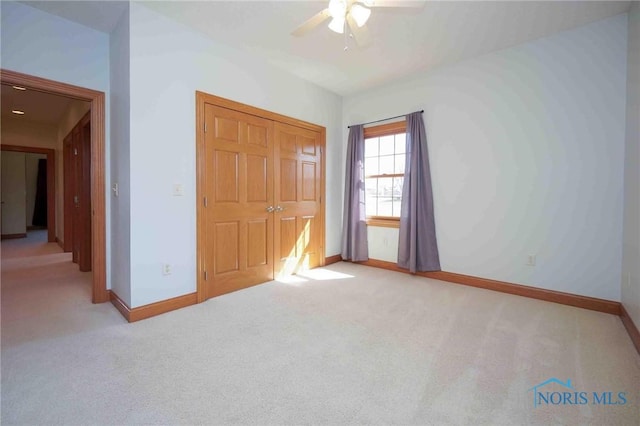 unfurnished bedroom featuring baseboards, carpet flooring, ceiling fan, and a closet