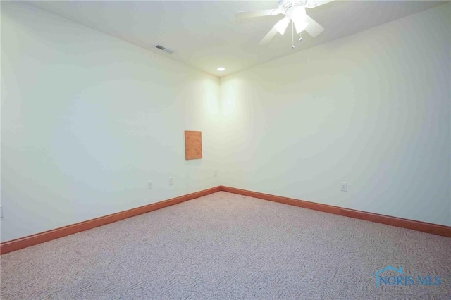 carpeted empty room with baseboards, visible vents, and a ceiling fan