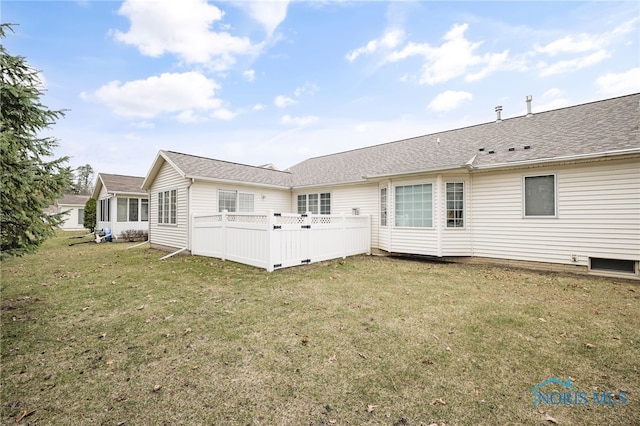 rear view of property featuring roof with shingles, fence, and a yard