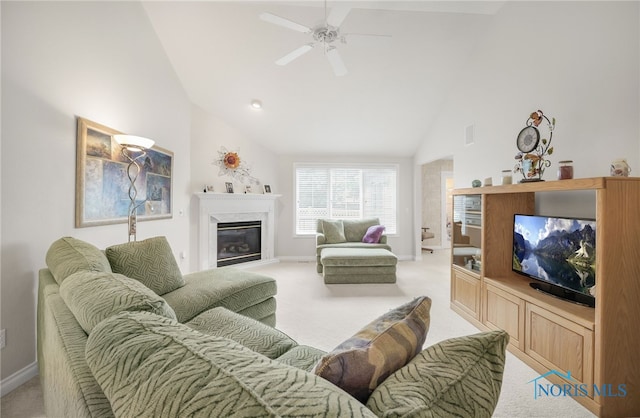 living area with high vaulted ceiling, a ceiling fan, a fireplace, baseboards, and light colored carpet