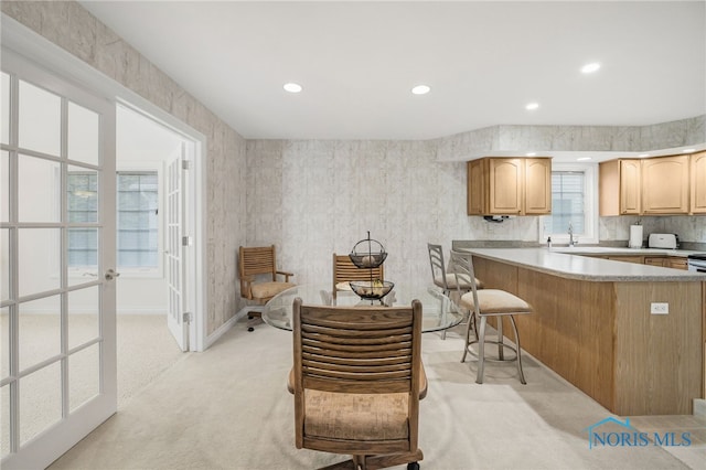 kitchen with light countertops, a kitchen bar, light colored carpet, recessed lighting, and light brown cabinets