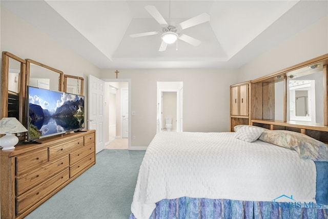 carpeted bedroom featuring baseboards, connected bathroom, a ceiling fan, lofted ceiling, and a tray ceiling