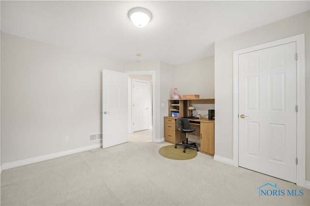office space with baseboards, visible vents, and light carpet