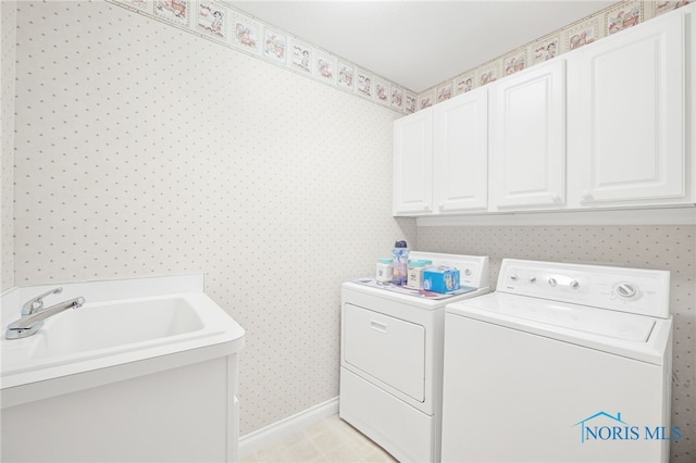 laundry area featuring washing machine and clothes dryer, cabinet space, wallpapered walls, and baseboards