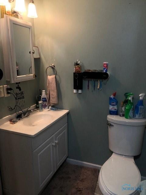 bathroom with baseboards, toilet, and vanity