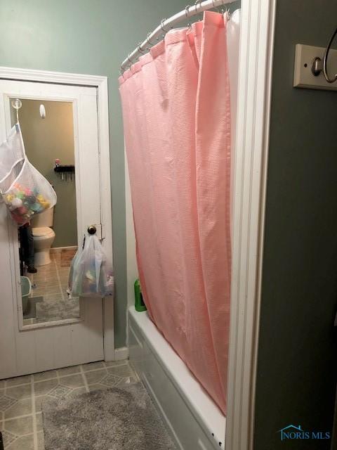bathroom featuring shower / bath combination with curtain, tile patterned floors, and toilet