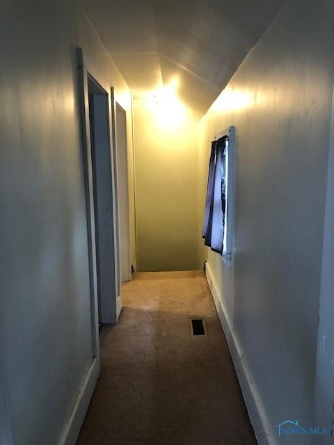 hall with visible vents, carpet floors, and vaulted ceiling