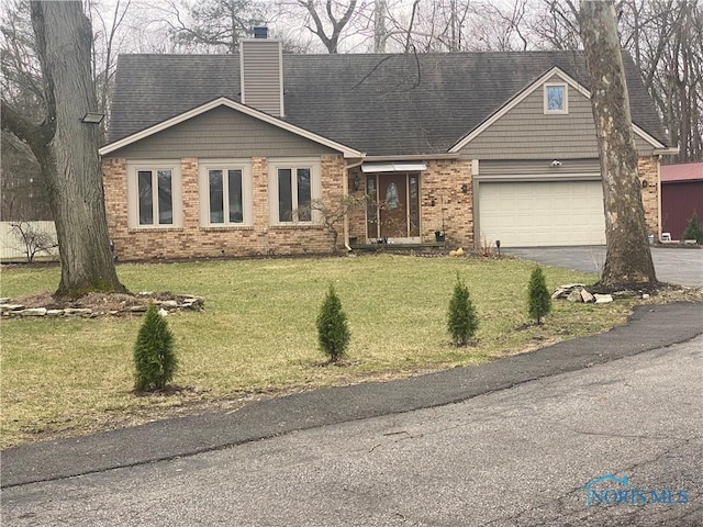 view of front of house featuring a front yard, a chimney, brick siding, aphalt driveway, and a garage