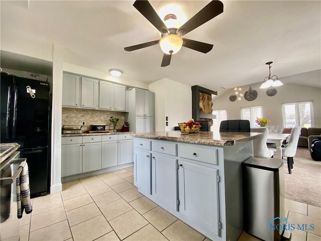 kitchen with vaulted ceiling, a center island, backsplash, freestanding refrigerator, and a ceiling fan