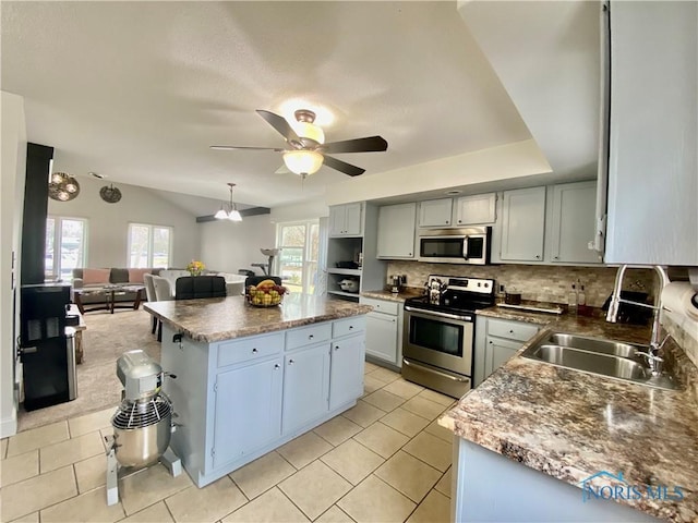 kitchen featuring tasteful backsplash, a kitchen island, a sink, ceiling fan, and appliances with stainless steel finishes